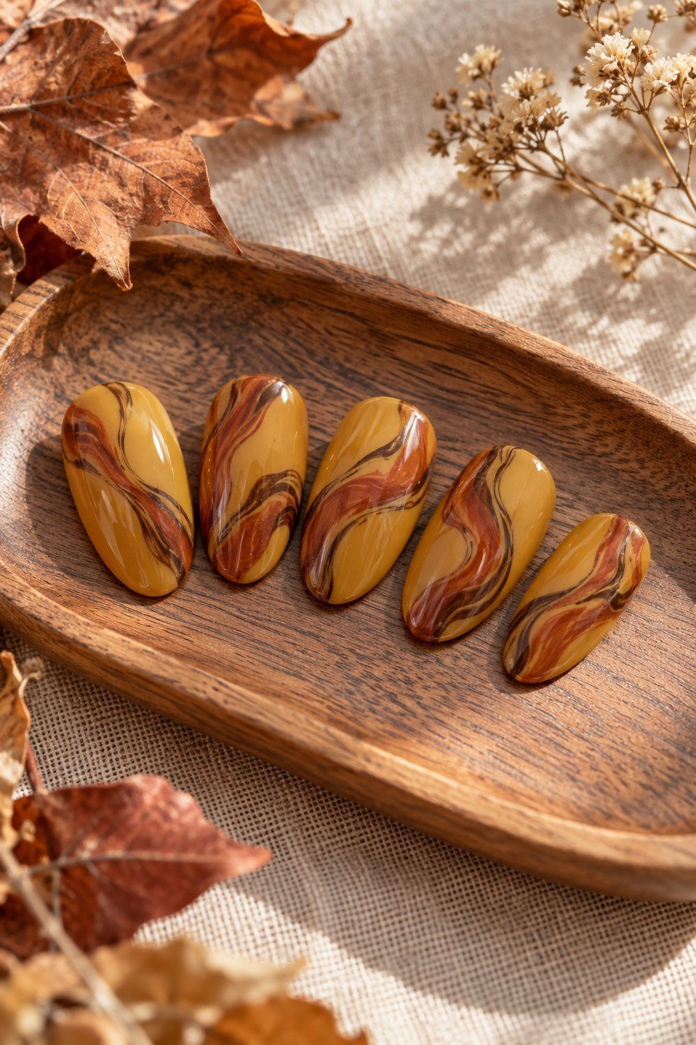 Ochre oval nail tips swirled with rust and dark brown marble